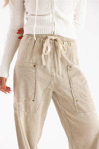 Beige corduroy cargo pants with a drawstring waist, worn by a model in a white ribbed sweater against a plain white background.