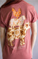 A person wearing a dusty rose short-sleeve T-shirt, shown from the back. The shirt features a large graphic print of a cow, sheep, and chicken in cream, orange, and brown tones, with the text 'simply southern collection' printed below.