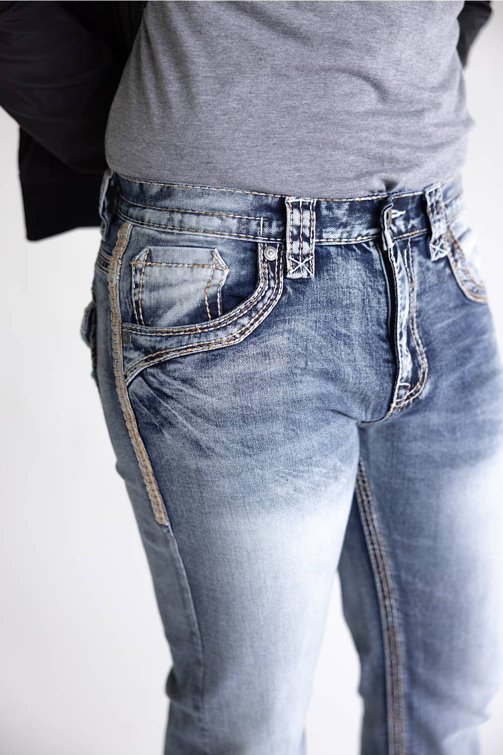 Close-up of a person wearing light blue denim jeans with a faded wash, showing the front and side pockets, waistband, and belt loops against a plain light background.