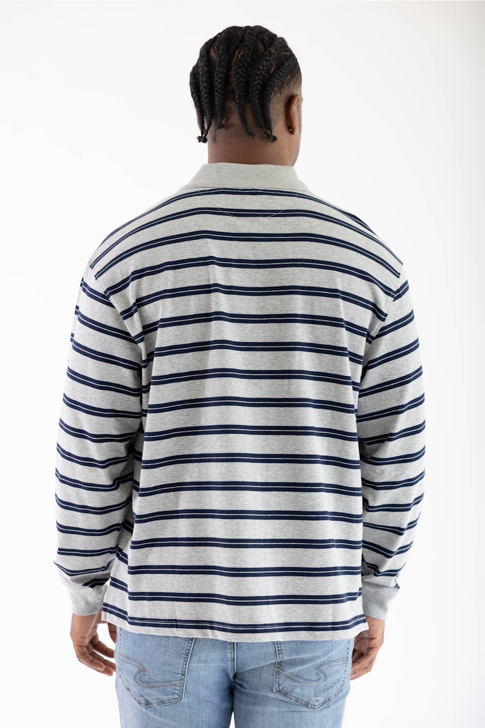 A man viewed from behind wearing a long-sleeve collared shirt with horizontal navy blue and off-white stripes, paired with light blue jeans, against a plain white background.