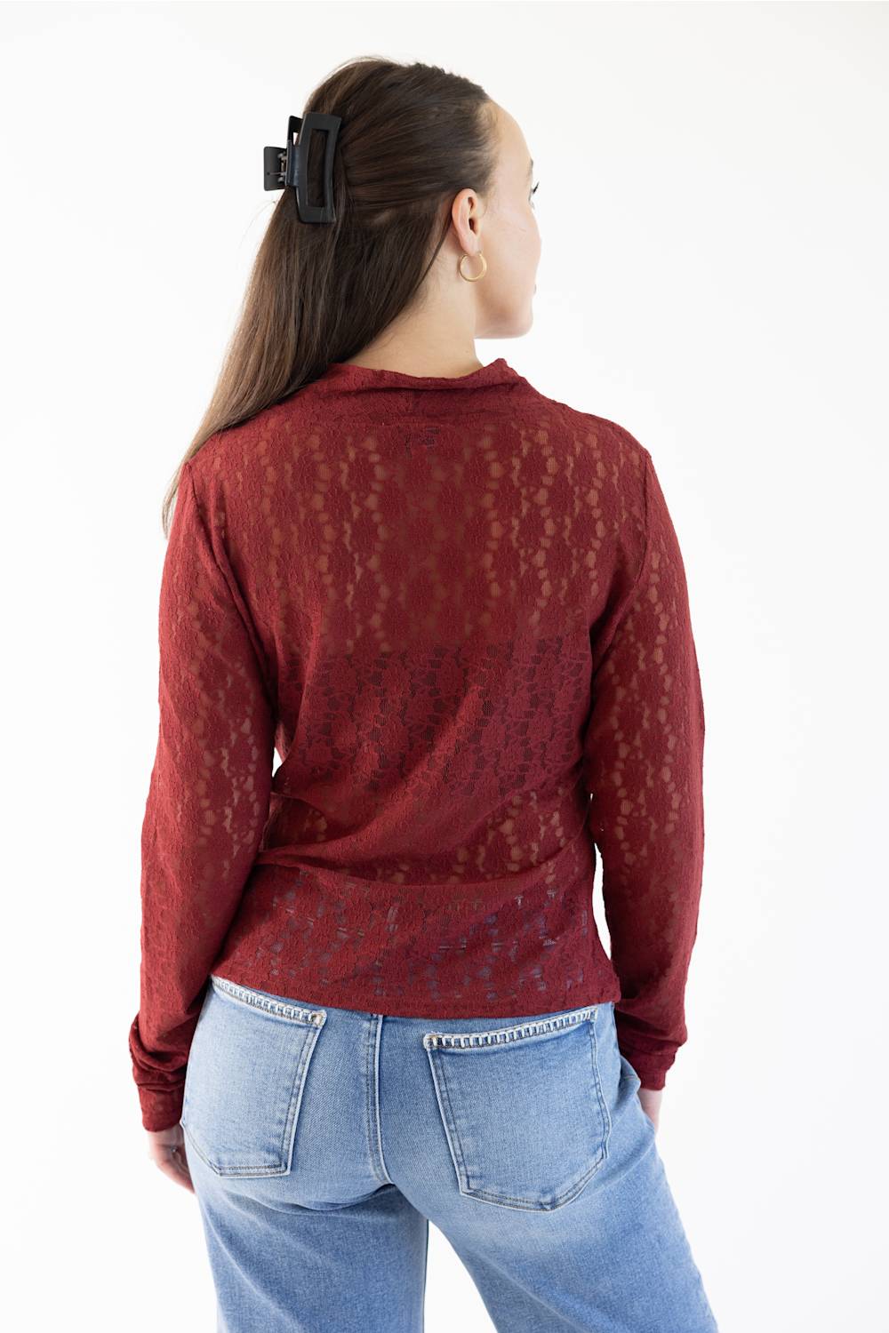A woman shown from the back wearing a long-sleeve maroon lace knit top and light blue jeans against a plain white background.