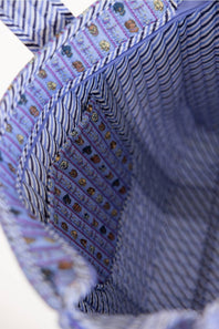 Close-up of a fabric tote bag interior with blue and white striped fabric and a purple side panel featuring small illustrated motifs.