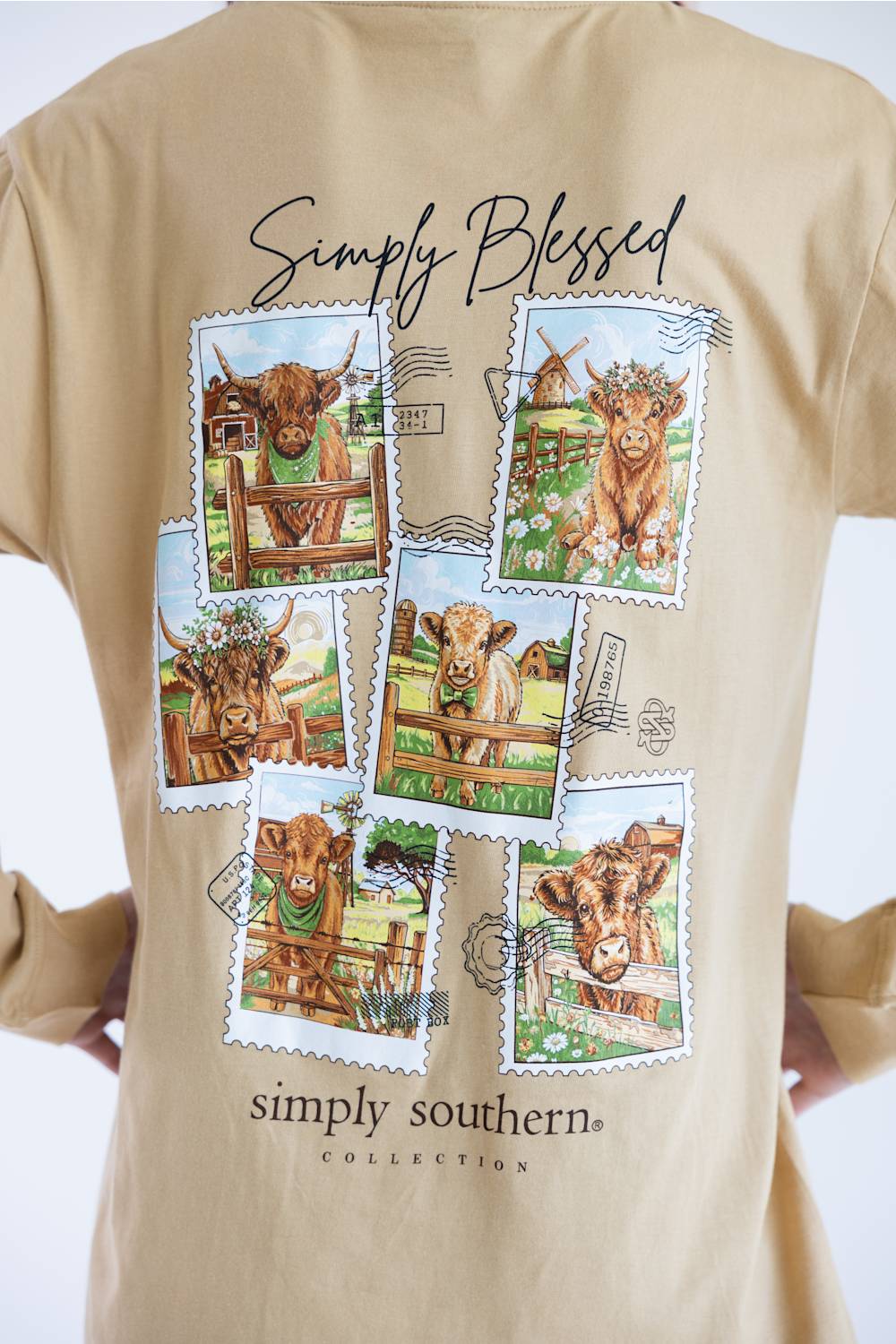 A beige t-shirt featuring a back graphic print with six postage stamp illustrations of Highland cows and the text 'Simply Blessed' and 'simply southern COLLECTION'.