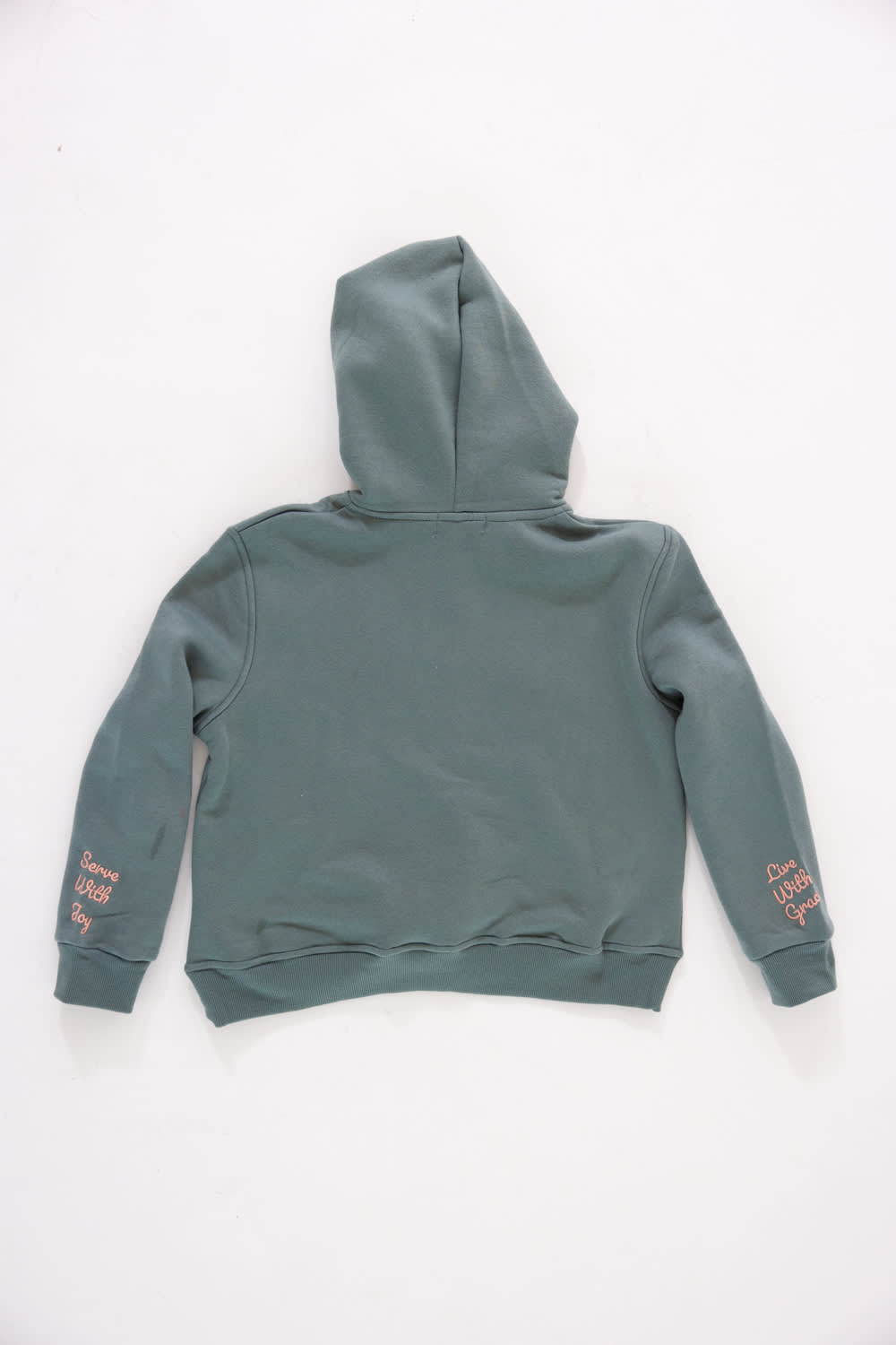 Back view of a girls' gray pullover hoodie featuring pink embroidered cursive text reading “Serve With Joy” on the left sleeve cuff and “Live With Grace” on the right sleeve cuff against a plain light background.