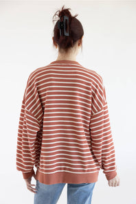 Women viewed from back wearing dusty mauve sweatshirt with white horizontal stripes and blue denim jeans on a basic background