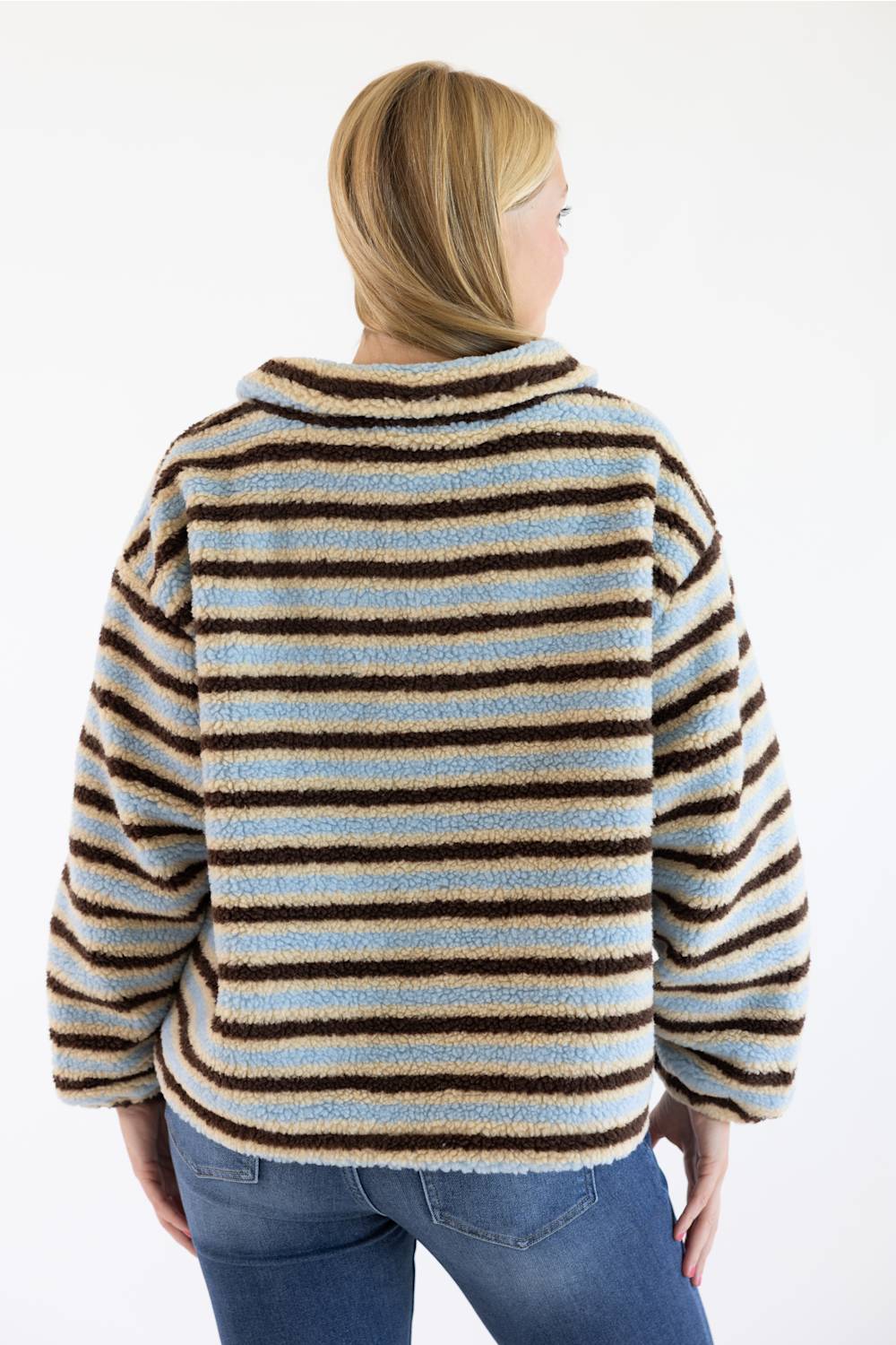 A woman viewed from the back wearing a fuzzy striped sherpa cardigan with horizontal brown, beige, and light blue stripes, paired with blue jeans against a plain white background.