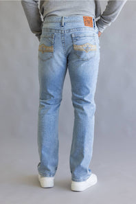 A person shown from the back wearing light-wash blue jeans with decorative gold embroidery on the back pockets, a gray long-sleeve top, and white sneakers against a neutral gray studio background.