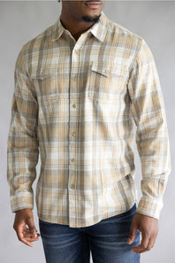 Close-up torso view of a model wearing the Split Men's long-sleeve flannel shirt in a beige, white, and light blue plaid pattern, featuring two chest flap pockets with button closures against a grey studio background.