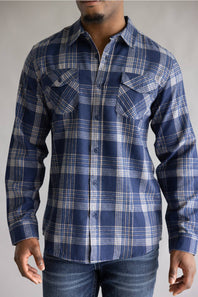 Close-up front view of a model wearing the Split Men's long-sleeve flannel shirt in a navy blue, khaki, and white plaid pattern, featuring two chest flap pockets with button closures against a grey studio background.