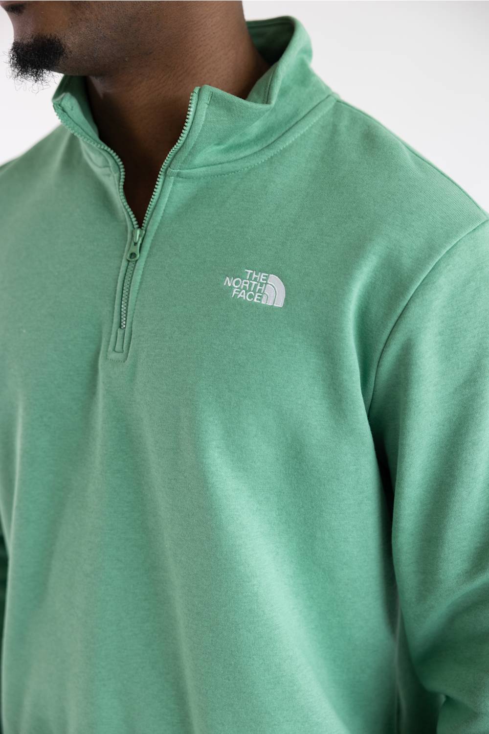 A close up of a man wearing the The North Face Evolution Simple Dome ¼ Zip Neck for Men in Dimmed Algae Green with a white The North Face Logo on the upper left chest.