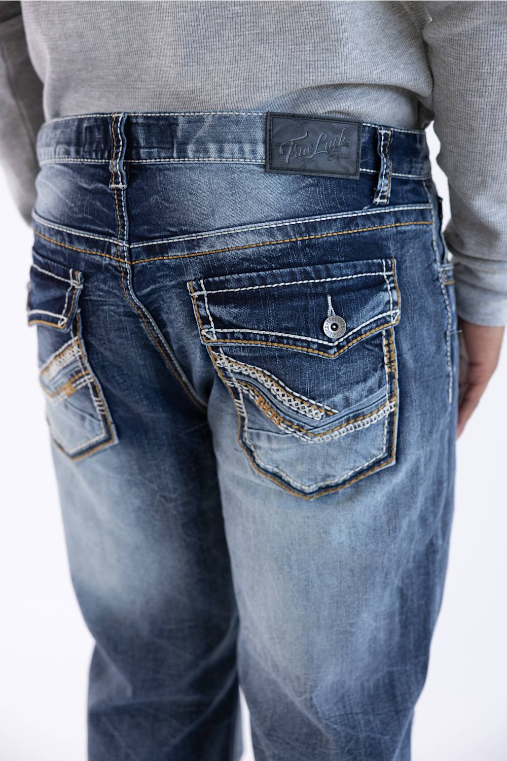 Back view of men's dark wash loose straight-leg denim jeans featuring embellished flap back pockets with contrast stitching and a branded leather waistband patch.