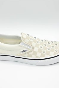 A Vans slip-on platform sneaker in a cream and white checkerboard pattern, decorated with silver studs, shown against a light gray background.