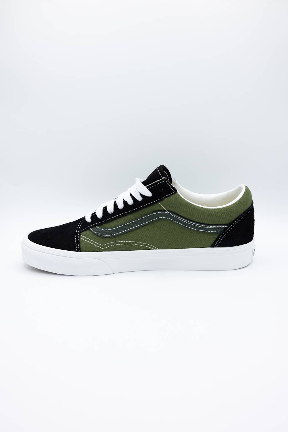 A low-top Vans platform sneaker in olive green and black canvas with white laces and a thick white rubber sole, shown from a side profile on a light gray background.
