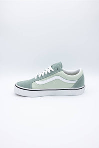 A classic low-top Vans sneaker in a muted sage green colorway, featuring white laces, a white side stripe, and a white rubber sole with a thin black stripe.
