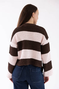 A woman from the back wearing a brown and light pink striped knit crew neck sweater and dark blue jeans against a white background.