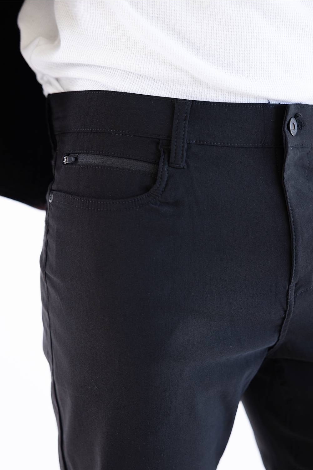 Close-up of a person wearing dark charcoal gray trousers with a white shirt tucked in, showing the back pocket and button area.