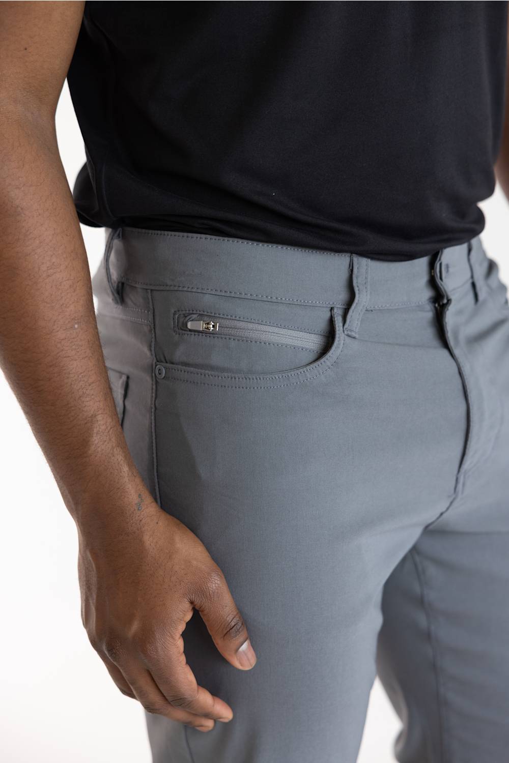 Close-up of a person wearing gray slim-fit trousers with a zippered side pocket, paired with a black shirt against a plain white background.