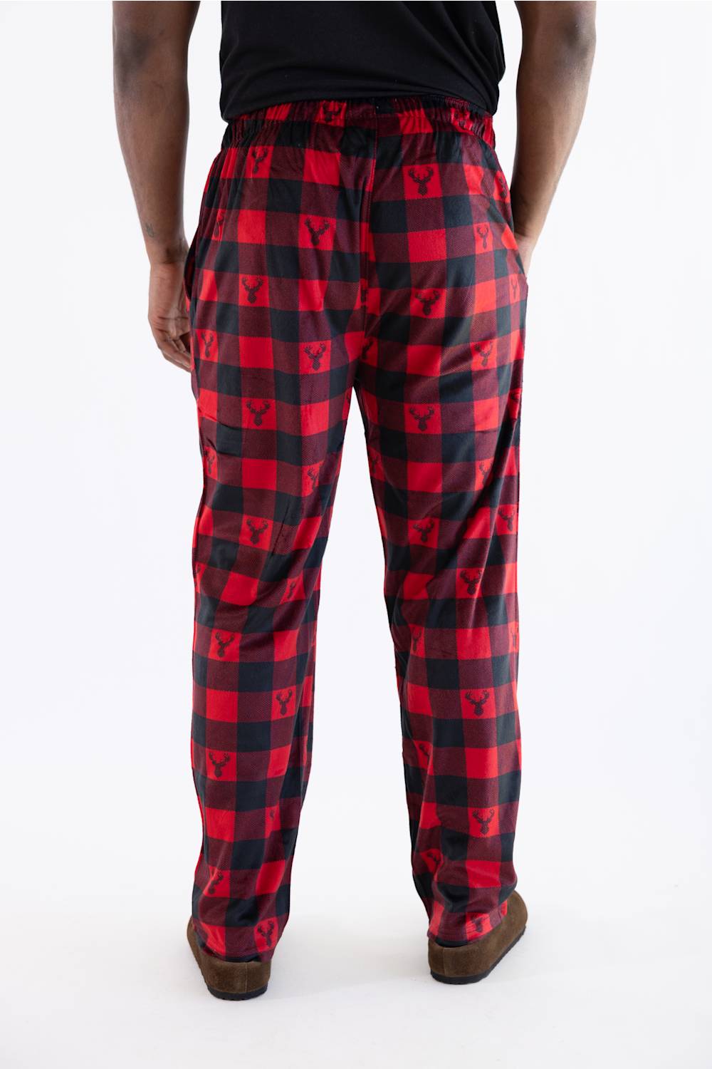 Red and black buffalo plaid pajama pants with a repeating deer  pattern, shown on a model from the back against a white studio background.