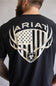 Back view of a man wearing a black t-shirt featuring a large distressed graphic of an American flag inside a shield with deer antlers and the Ariat brand name.