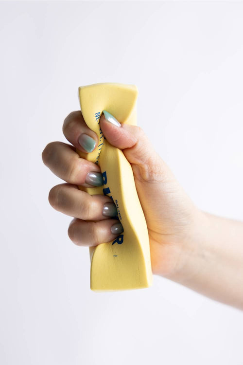 Hand holding a squishy butter toy against a white background