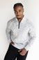 A man wearing a light gray and white marled knit quarter-zip sweater with black pants, standing against a plain white background.
