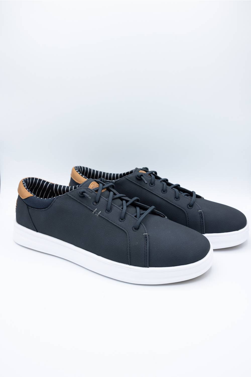 A pair of low-top casual sneakers in dark navy blue with white soles and a light brown leather heel tab, displayed on a clean white studio background.