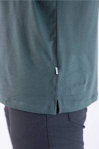 Close-up view of the back hem and side split of the 7Diamonds Core Crew T-Shirt in Drake green, showing the branded woven label tag.