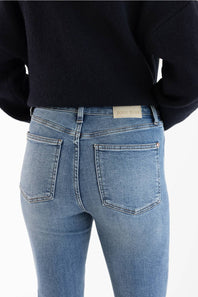 Rear view of a person wearing light blue skinny jeans and a dark navy sweater, showing the back pockets and a small 'Judy Blue' brand label on the waistband.