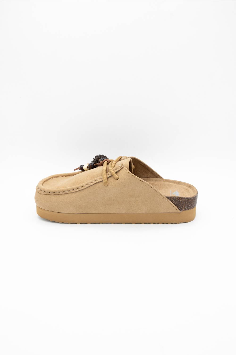 A single tan suede mule slipper with a decorative dark brown and black tassel on the laces, set against a plain white background.