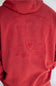 A close up of a man viewed from the back wearing a red pullover hoodie with a tonal embroidered logo across the back, photographed against a plain white studio background.