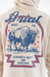 Close-up of the back of a beige hoodie featuring a large blue and red graphic print of a bison with the text 'Ariat BOOT CO.' and 'STRENGTH UNITY AND HERITAGE'.