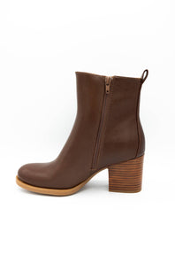 A brown leather ankle boot with a side zipper, a stacked wood-look block heel, and a light tan sole, shown from a side profile on a white background.