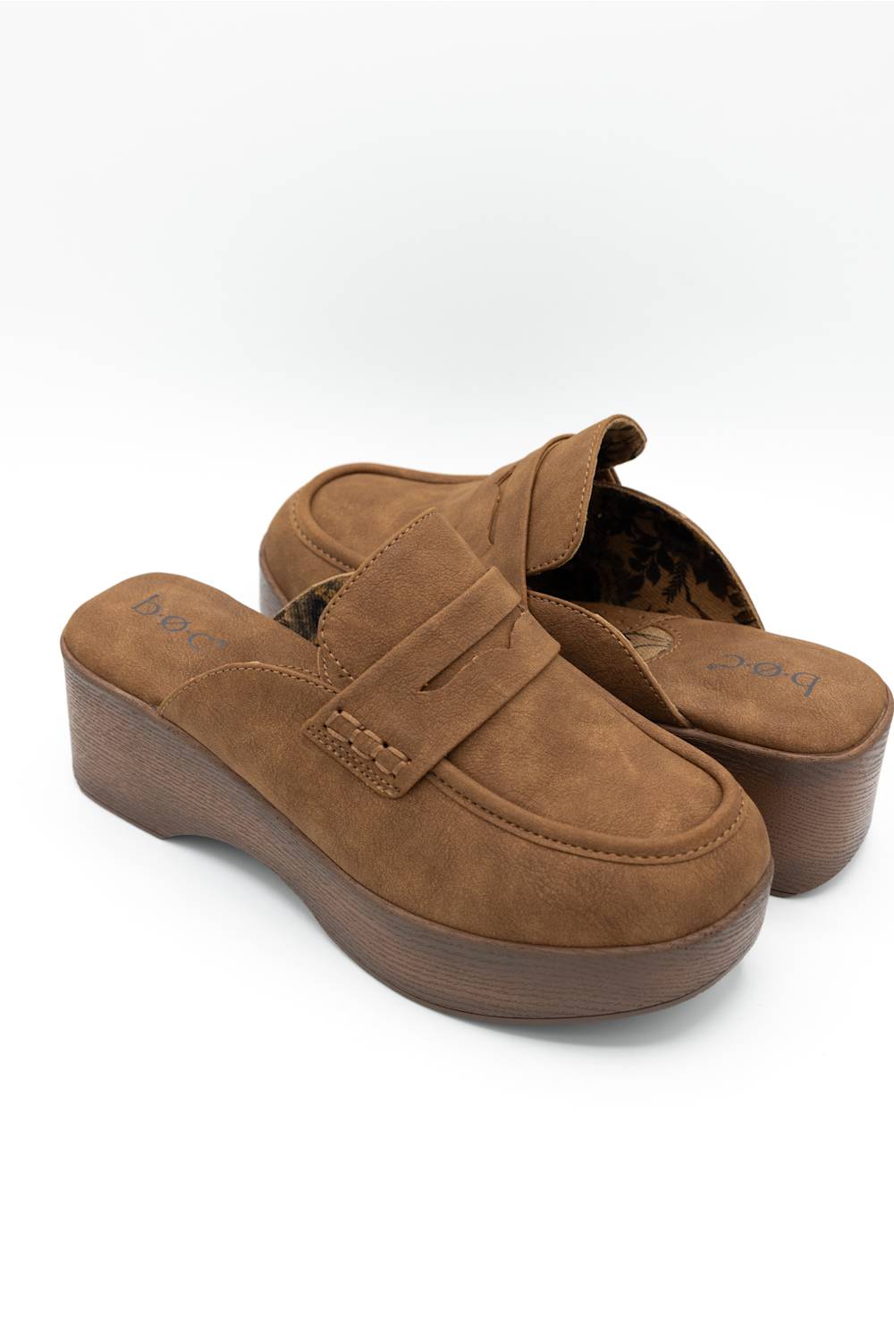 A pair of women's brown suede slip-on wedge mule shoes with a strap detail across the vamp, shown on a clean white background.