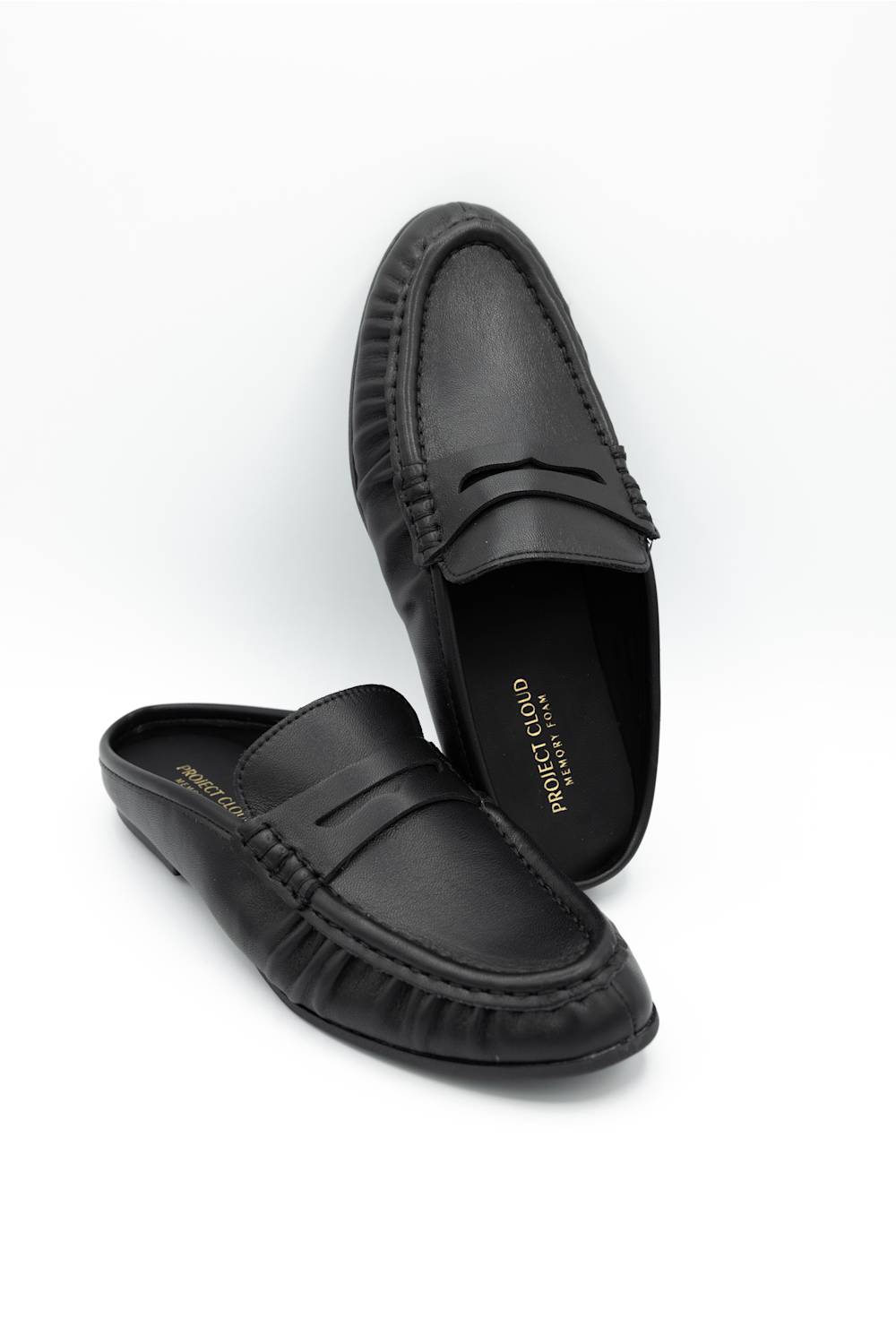 A pair of black leather penny loafers with decorative stitching around the toe, displayed on a clean white background. One shoe is positioned upright and the other lies flat on its side