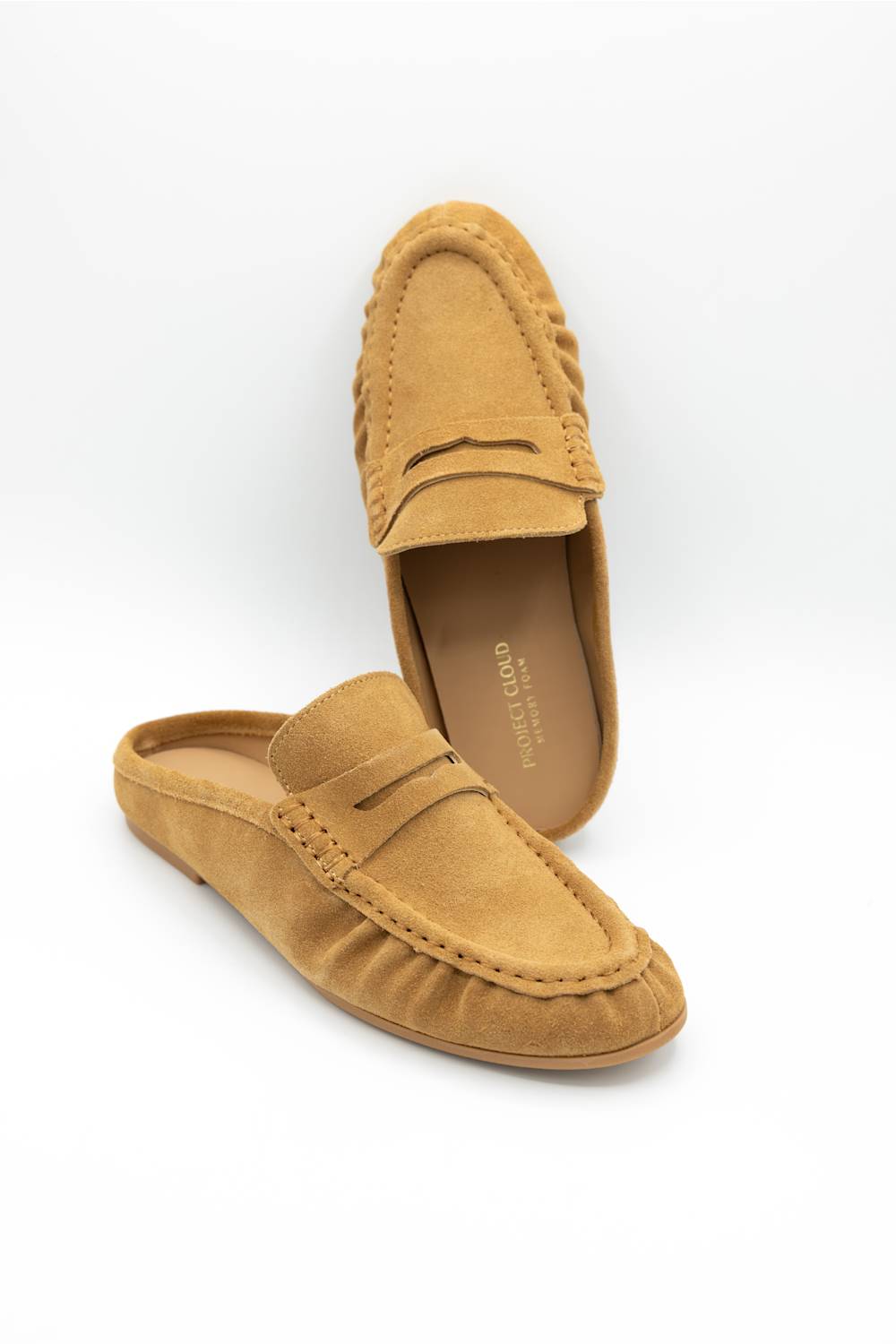 A pair of tan suede penny loafers, with one shoe standing upright and the other lying flat, showcasing the textured suede material 
