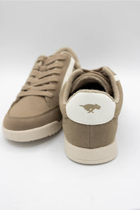 A pair of low-top sneakers in a warm taupe-brown suede and canvas mix, featuring beige laces, off-white soles, and a white heel tab with a brown kangaroo logo.