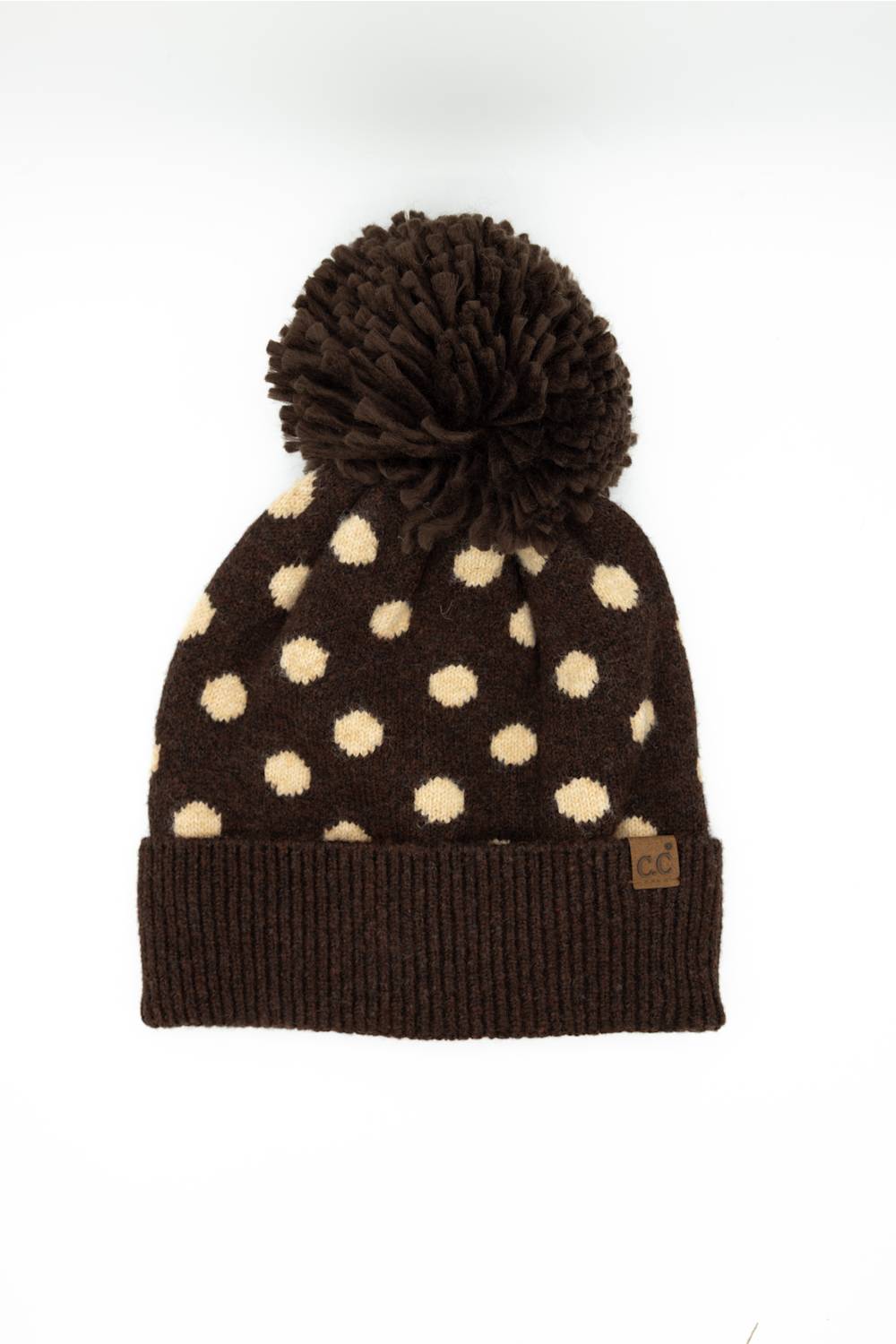 C.C. Polka Dot Pom Beanie for Women in Brown. Front product view of the knit hat, showing the brown main color, cream polka dots, dark brown fuzzy pom-pom, and ribbed cuffed hem.