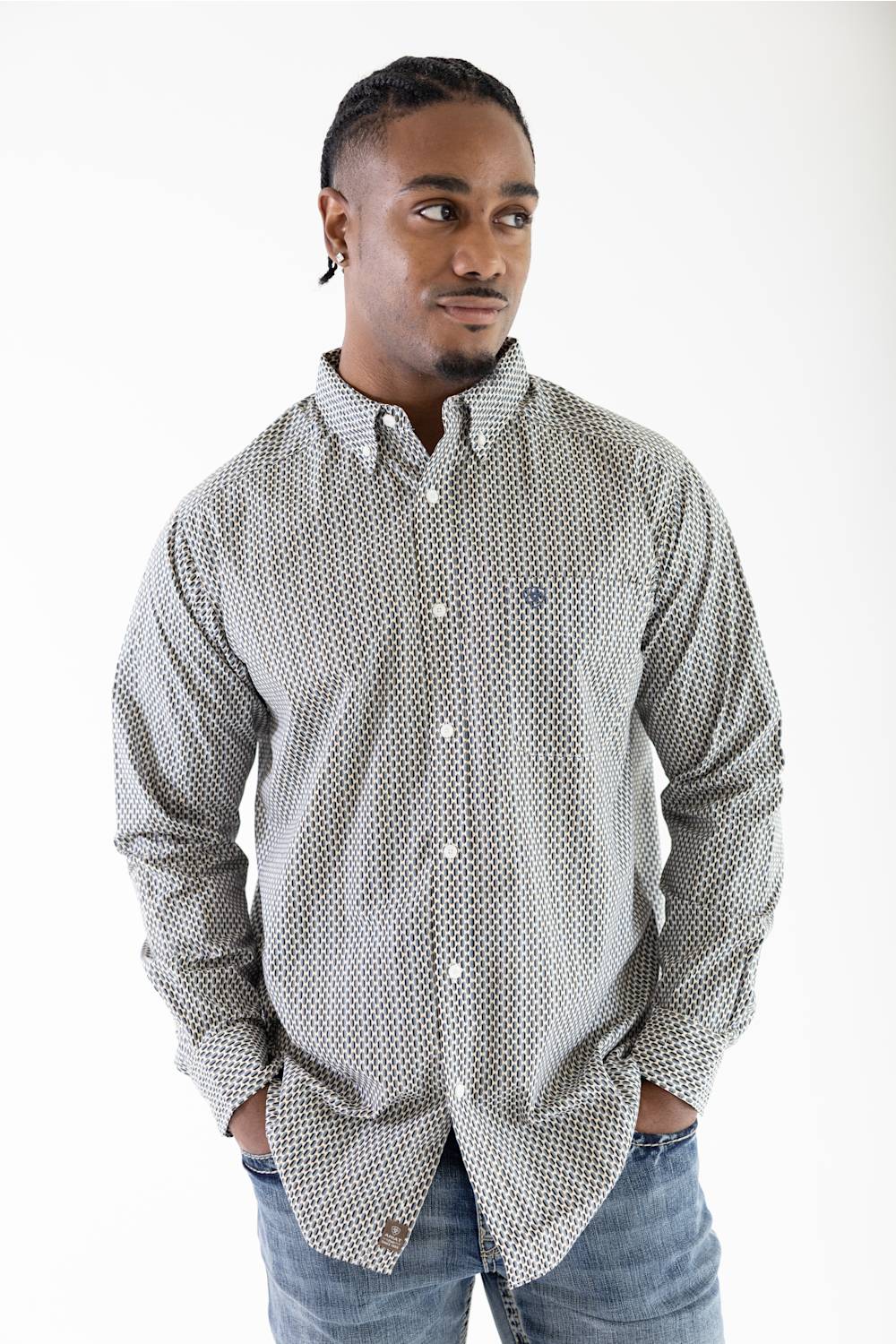 A man wearing a long-sleeve button-down shirt with a small white geometric pattern on a light gray background, paired with blue jeans, photographed against a plain white studio background.