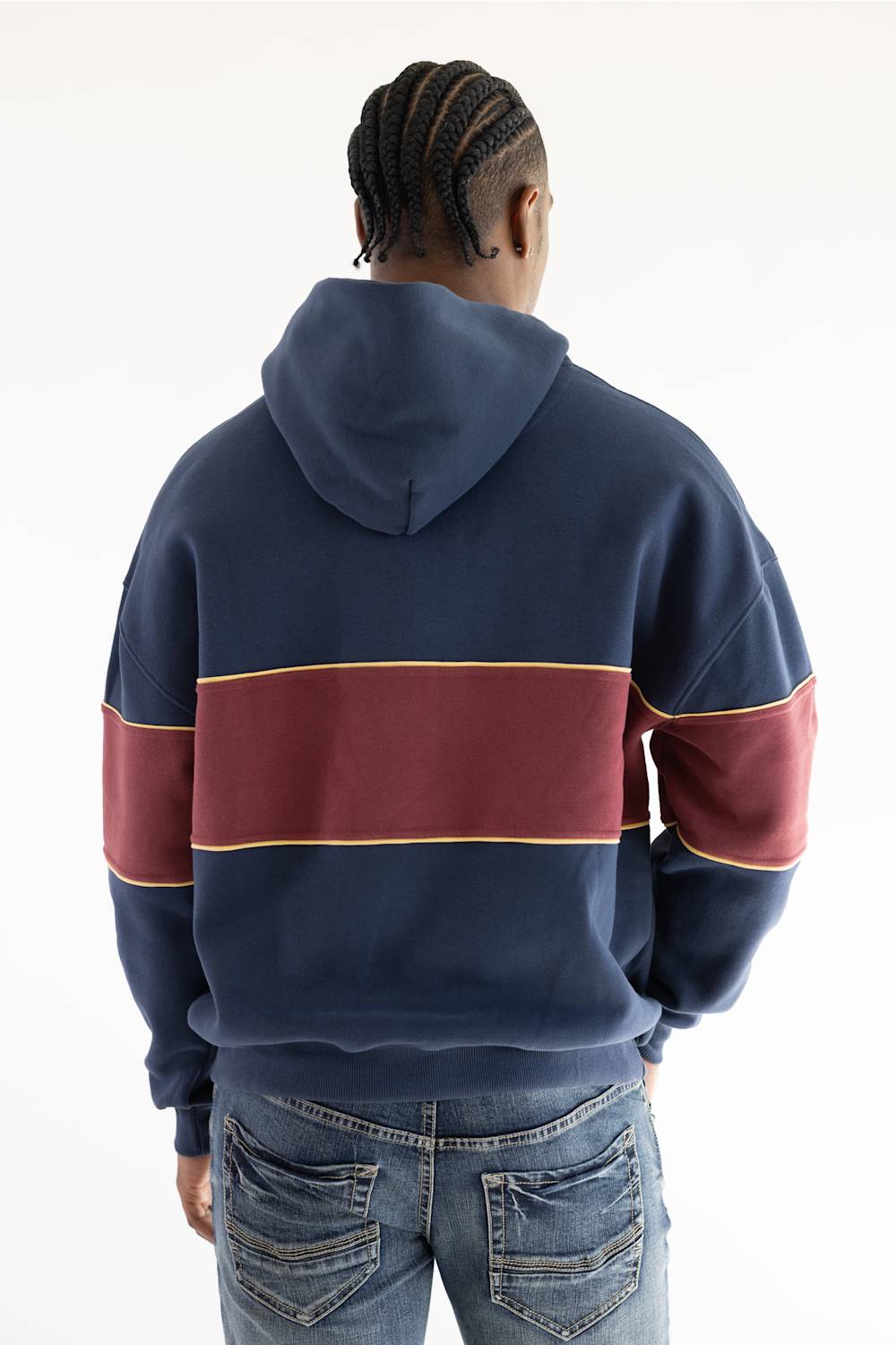 A person viewed from the back wearing a navy hoodie with a wide burgundy horizontal stripe across the upper back and sleeves, outlined with thin gold trim, paired with blue jeans against a plain white background.