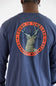 A close up of a man viewed from behind wearing a navy blue long-sleeve t-shirt with a large circular back graphic featuring a deer head and the text 'TOUGH IS TIMELESS' and 'CARHARTT WORKWEAR'.