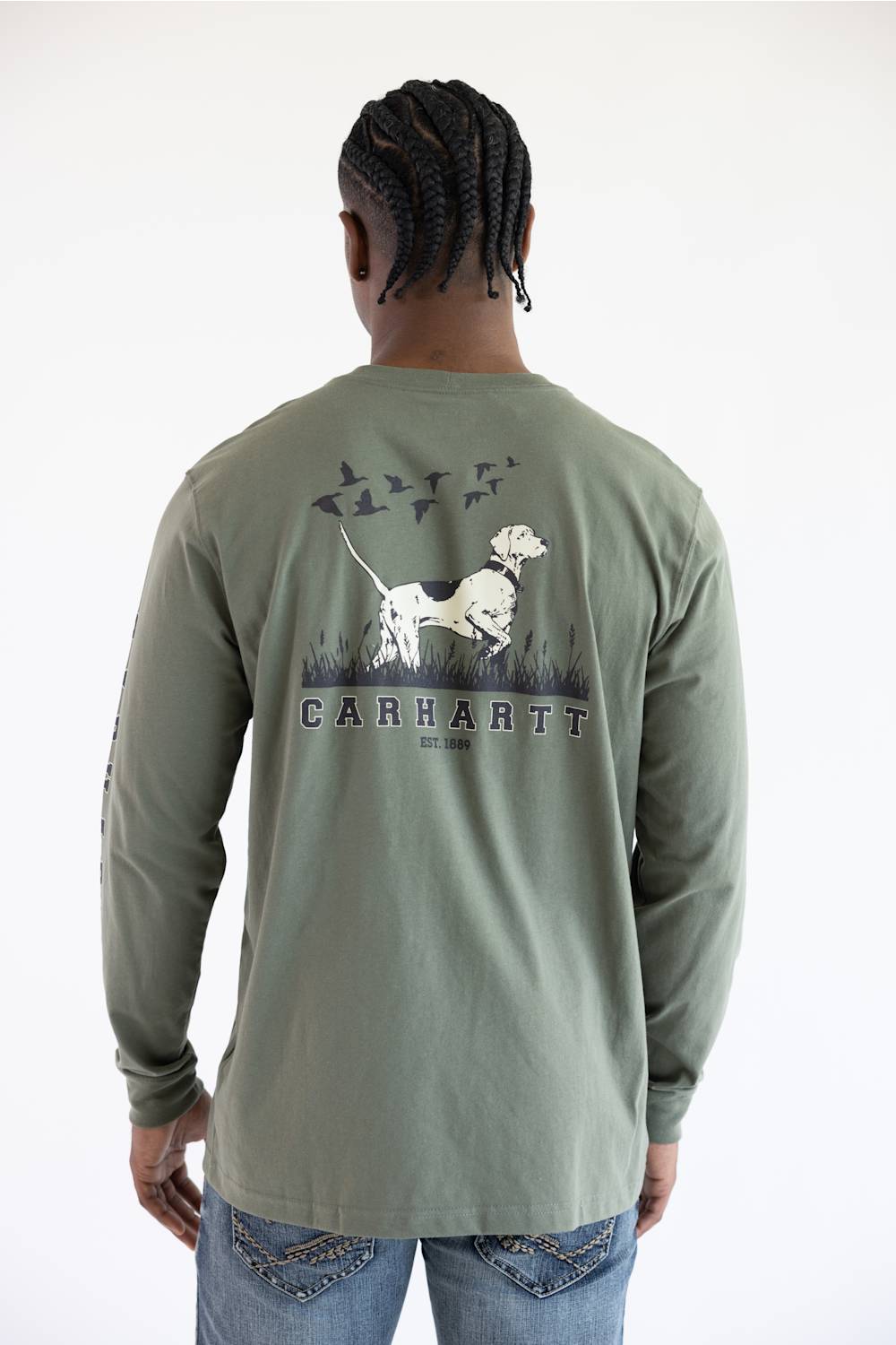 A man from the back wearing the Carhartt Irvine Relaxed Pointer Dog Long Sleeve T-Shirt for Men in Dusty Olive Green featuring a Carhartt logo down the left arm and pointer dog logo with birds on the back.