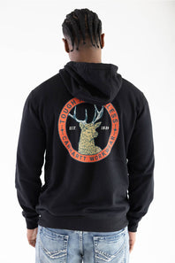 Back view of a male model wearing a black Carhartt Sawyer deer hoodie, showcasing the large circular back graphic with a deer illustration, "Tough is Timeless," and "Carhartt Workwear" text.