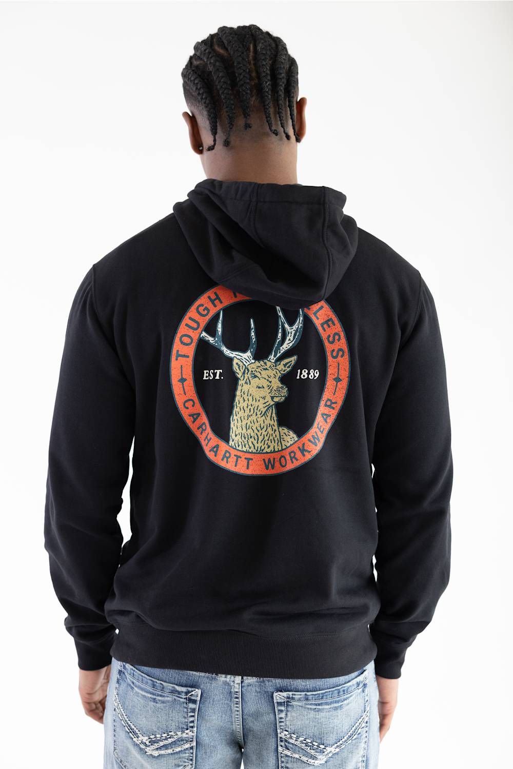 Back view of a male model wearing a black Carhartt Sawyer deer hoodie, showcasing the large circular back graphic with a deer illustration, "Tough is Timeless," and "Carhartt Workwear" text.