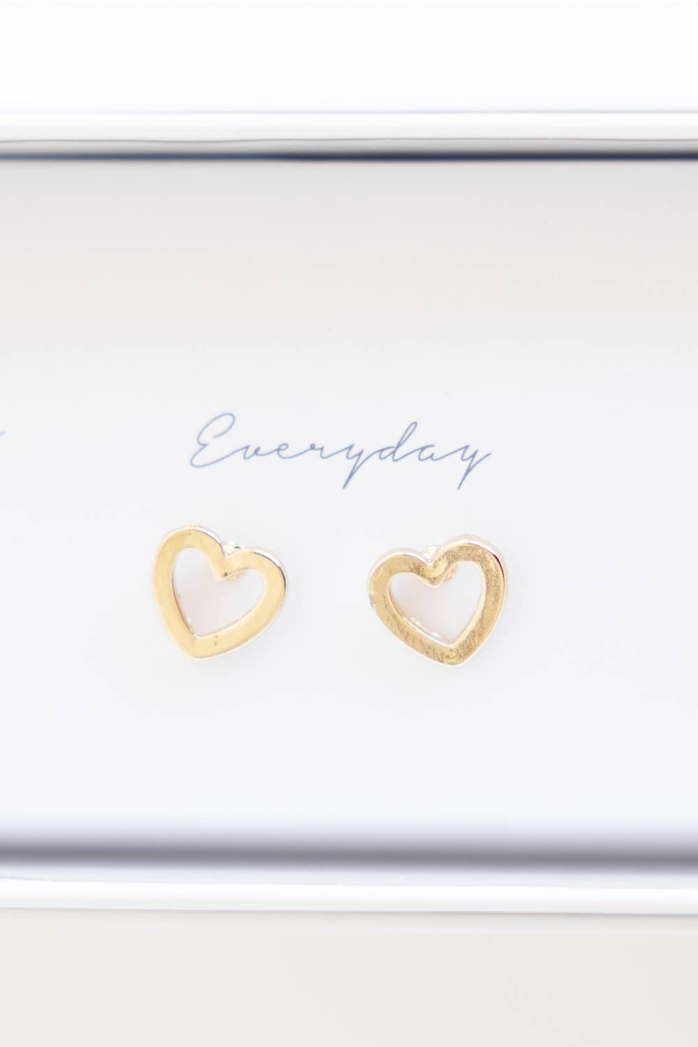 A pair of small open heart stud earrings in a gold-tone finish, displayed on a white card that reads 'Everyday'.
