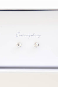A pair of small round stud earrings with clear faceted gemstones on a white display card that reads 'Everyday'.