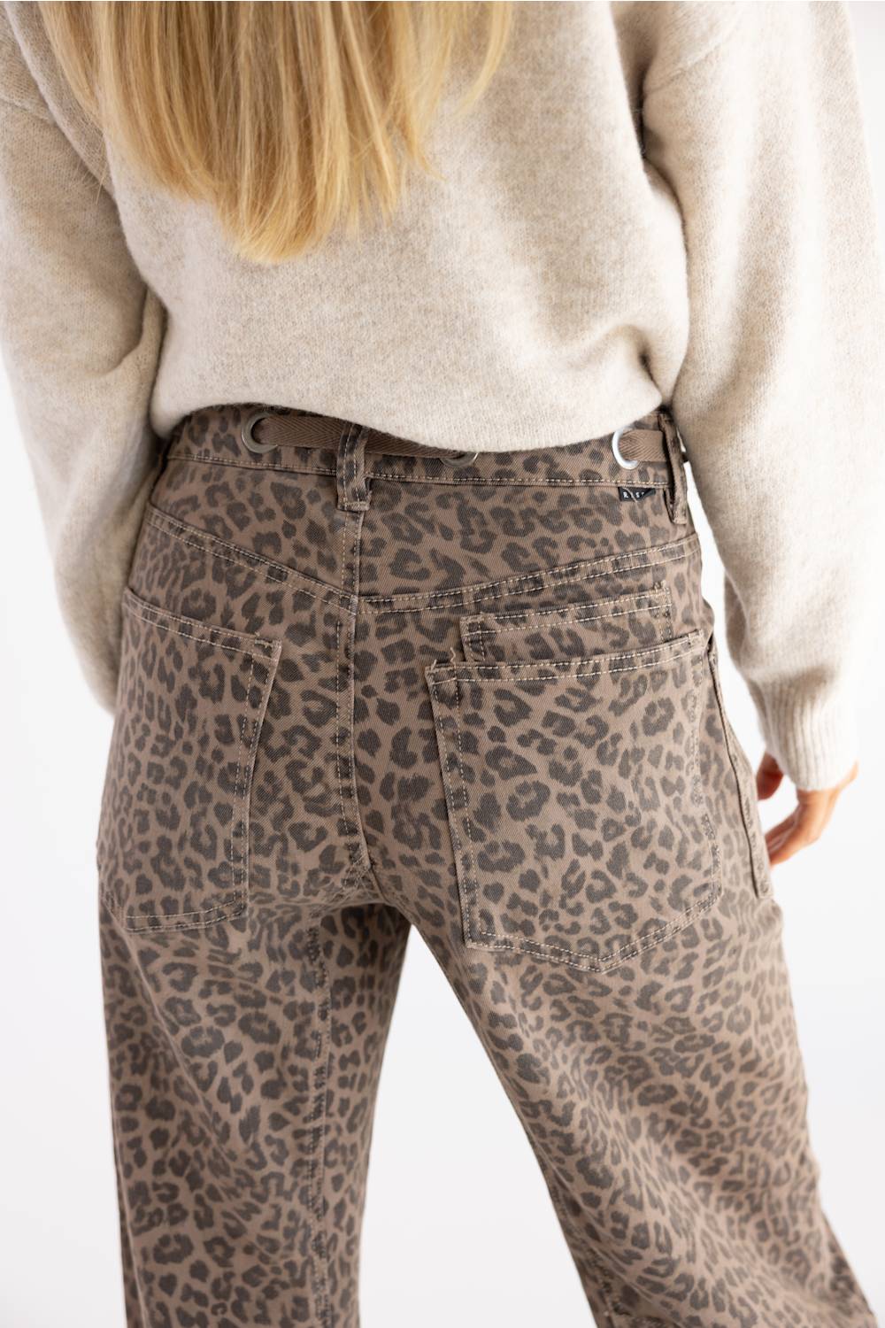 close up view of woman modeling cheetah print jeans with black boots and tan sweater 
