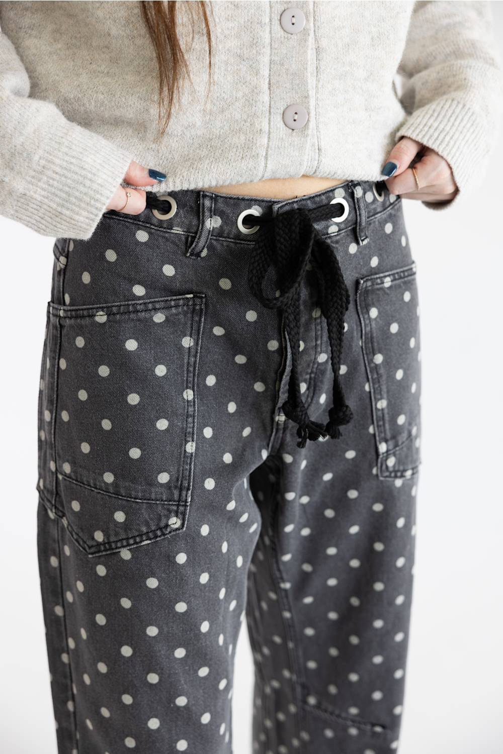 Close-up of Aaron & Amber Drawstring Polka Dot Barrel Jeans in black showing the drawstring waistband, eyelet details, and front pockets.