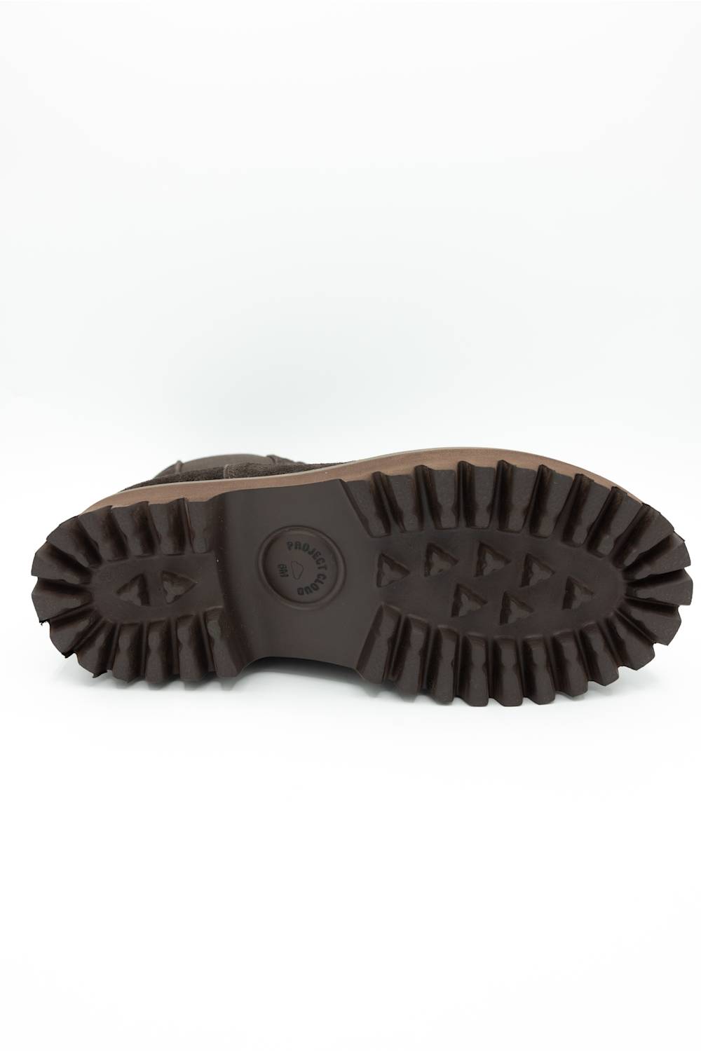 The rugged outsole of a brown boot, showing deep lugs and a circular embossed logo, photographed from underneath on a white background.