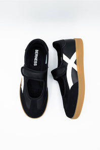 A pair of black Mary Jane-style shoes with white side stripes and gum soles, shown from top and side angles on a white background.