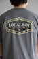 Local Boy Vintage Emblem T-Shirt for Men in Grey; Person wearing a gray t-shirt with 'Local Boy Outfitters' logo on the back.